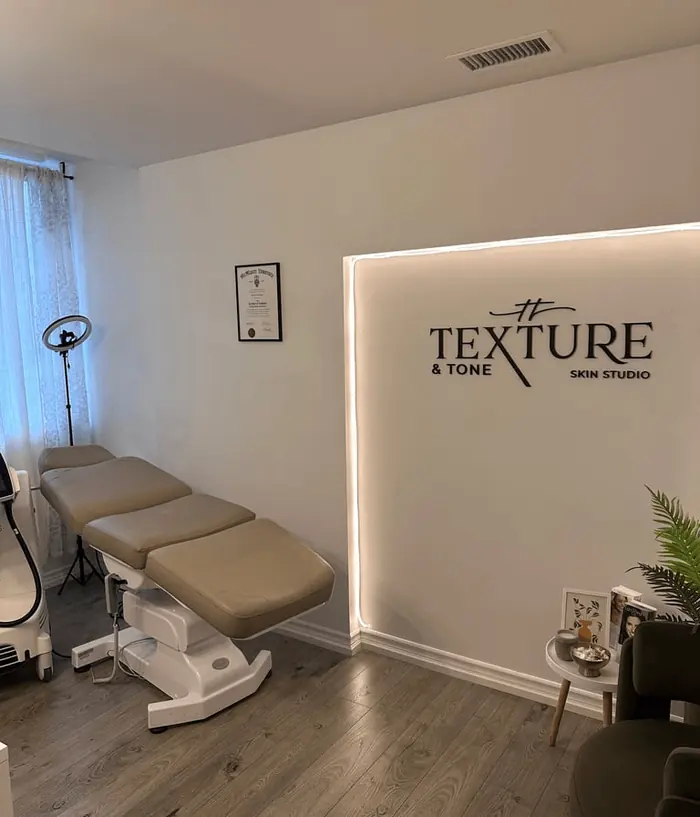 The treatment room, with the treatment bed and the Texture & Tone logo wall