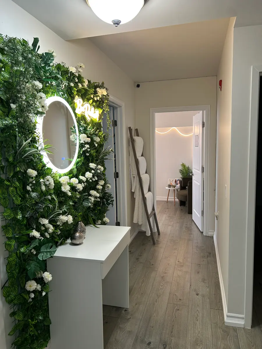 The entrance of the Texture & Tone studio, with a flower wall and lit mirror